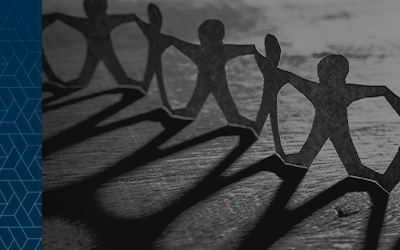 Row of paper dolls casting a shadow over a wooden table